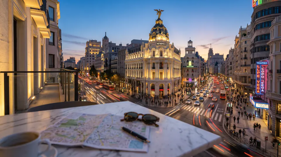 Mapa de Madrid y gafas de sol frente a la Gran Vía al atardecer